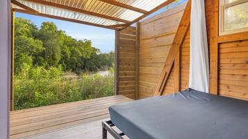 A wooden cabin with a bed, a window, and a view of a forest.