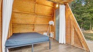 A small, single-room cabin with a bed, a fan, and a window. - The Camellia - A Frame Camping Pod w/ River View (Easley)