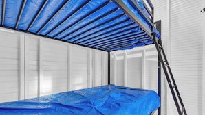 A bunk bed with a blue mattress cover, a ladder, and white walls. - The Daffodil - Cozy Camping Pod w/ River View (Easley)