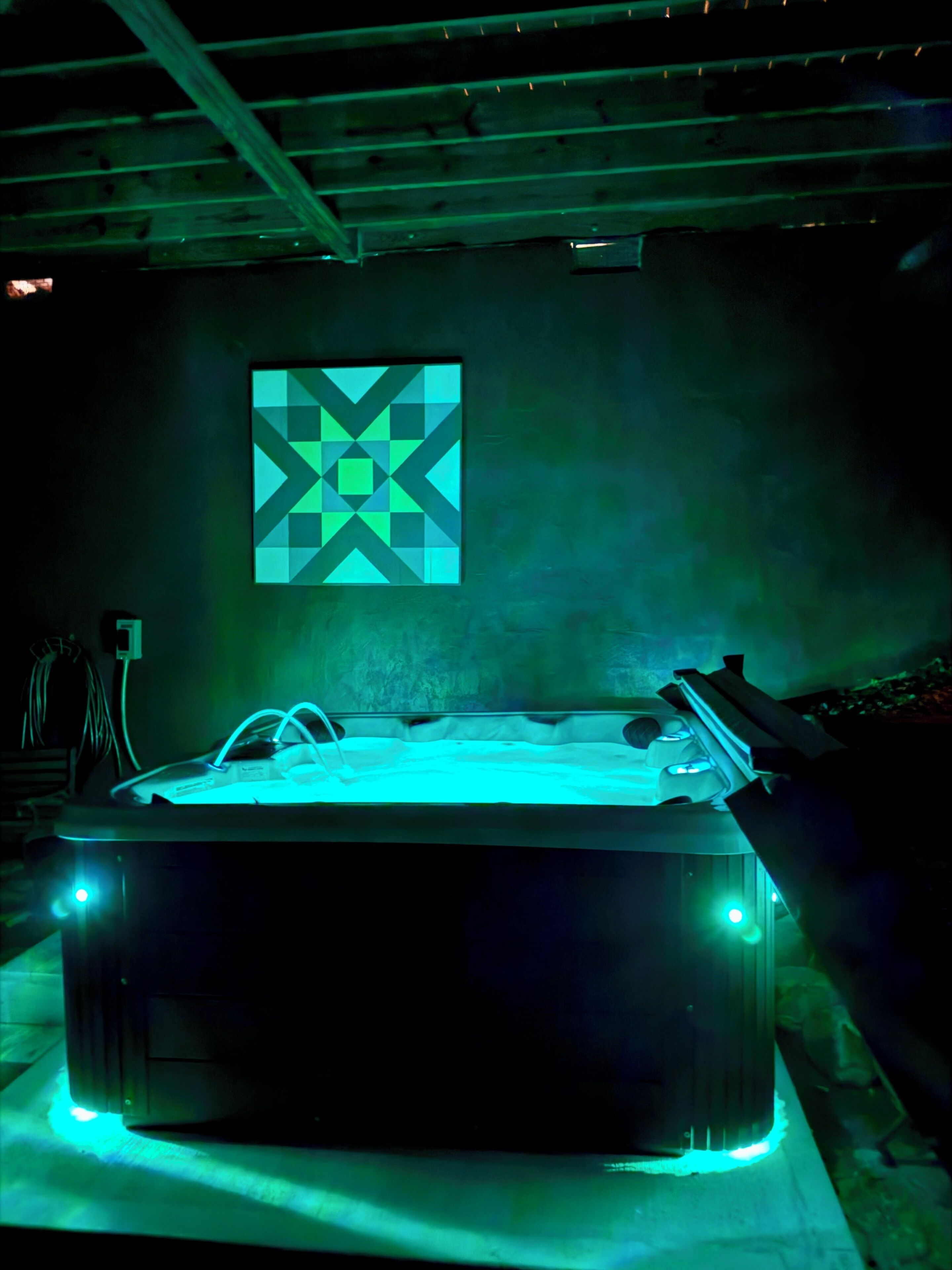 A room with a large, rectangular pool table in the center, surrounded by walls with a geometric patterned mural.