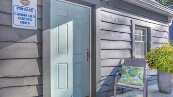 A private entrance with a closed door, a bench with a cushion, and a potted plant.