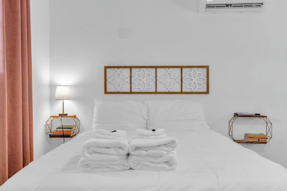 Une chambre d’hôtel avec un lit soigneusement fait, une lampe de chevet et une œuvre d’art accrochée au mur.