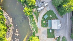Vista aérea de una propiedad con río, zonas verdes y un edificio de techo plano.