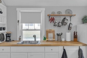 Eine Küche mit einer Holzausziehtheke, einem Spülbecken und einem Fenster mit mattiertem Glas.