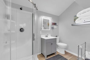 A modern bathroom with a glass shower enclosure, a white sink, a toilet, and a towel rack.