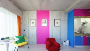 Une cuisine moderne avec un évier et des placards, un coin repas avec une table et des chaises, et un mur coloré orné de tableaux.