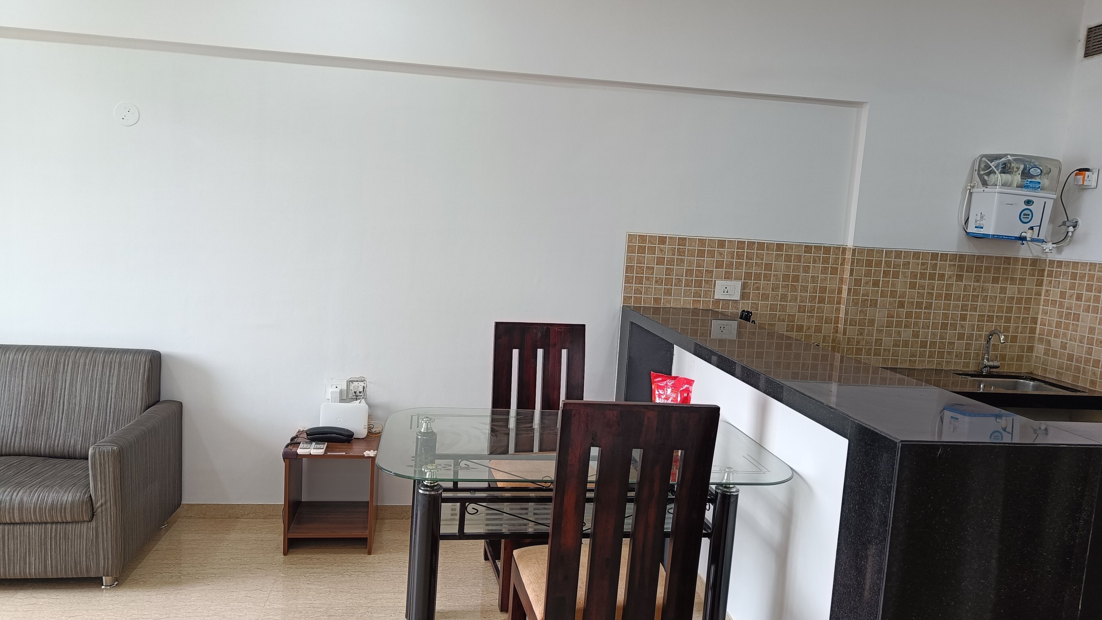 Una cocina compacta con una mesa de vidrio, un sofá y una pequeña mesita auxiliar.