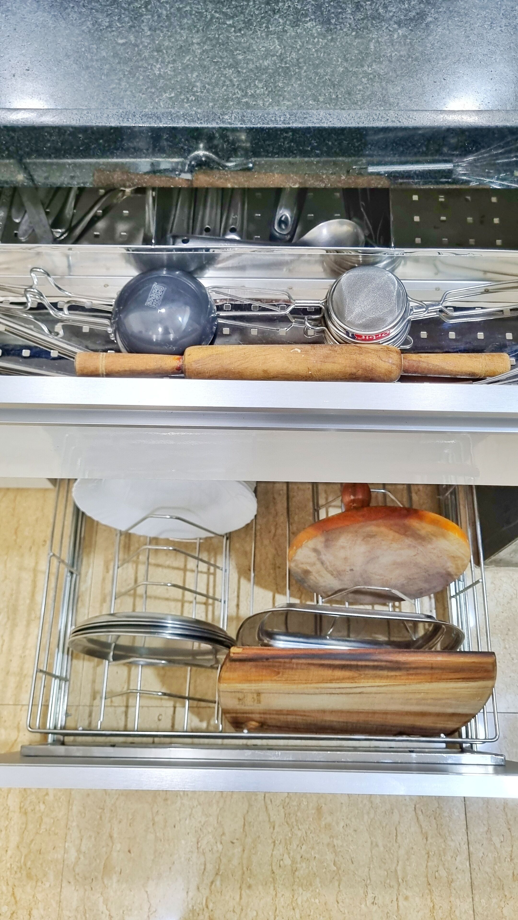 Een keuken met een rvs spoelbak, een houten snijplank en een metalen vergiet.