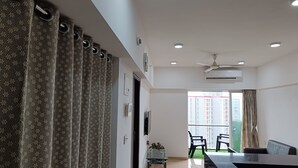 Ein modernes Wohnzimmer mit Glastisch, zwei Stühlen, Deckenventilator und Klimaanlage.