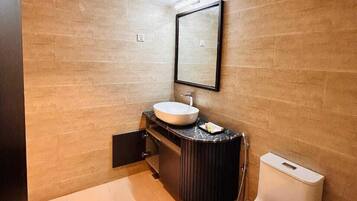 A modern bathroom with a large sink, a mirror, and a toilet.