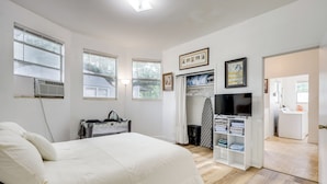 Ein Schlafzimmer mit Bett, Fernseher, Kleiderschrank und einer Waschgelegenheit.