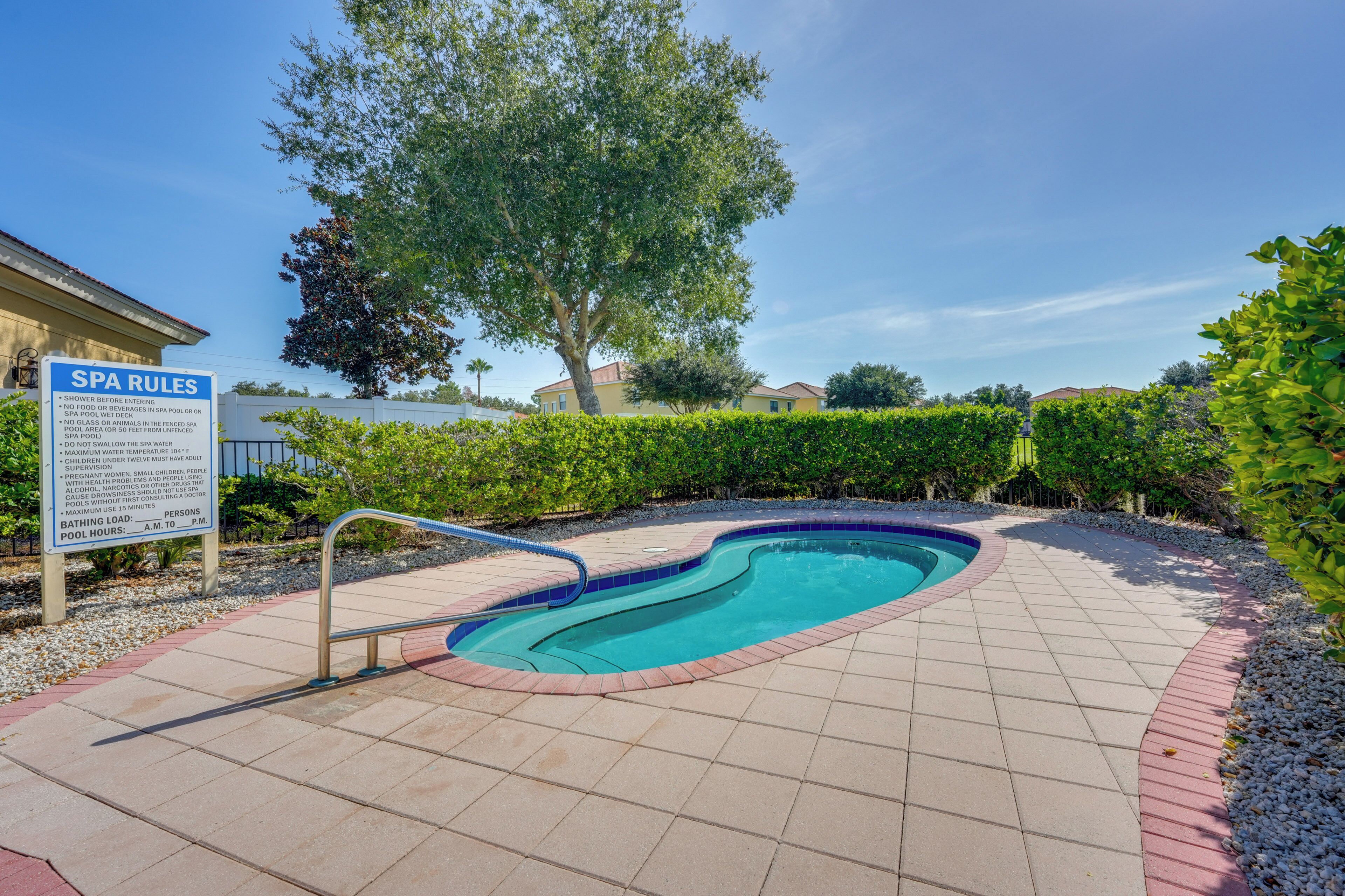 Un espace de détente avec piscine et panneaux indiquant les règles à respecter, entouré de verdure et sous un ciel dégagé.