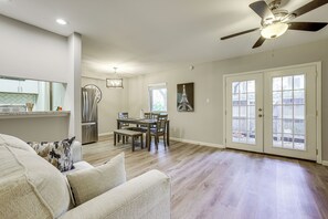 Un amplio espacio de sala con una mesa de comedor, un ventilador de techo y un gran ventanal.