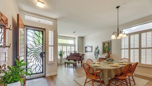 A dining area with a piano, wooden chairs, a table set for four, and a large window with blinds. - Extended-stay Oasis: Gilbert Getaway w/ Office! (Gilbert)