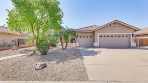 A residential area with a house featuring a garage, a driveway, and a landscaped garden with rocks and a tree. - Extended-stay Oasis: Gilbert Getaway w/ Office! (Gilbert)