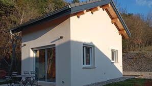 Uma casa moderna com varanda, porta de correr de vidro e um pequeno jardim.