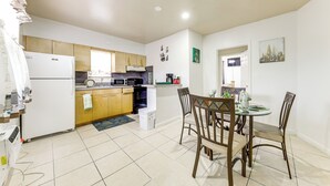 Una cocina compacta con electrodomésticos modernos, una zona de comedor con sillas de madera y una pequeña mesa.