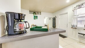 Una cocina con cafetera, una bandeja verde y una puerta que da a otra habitación.