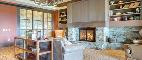 A spacious living room with a fireplace, wooden shelving, and a patterned carpet.