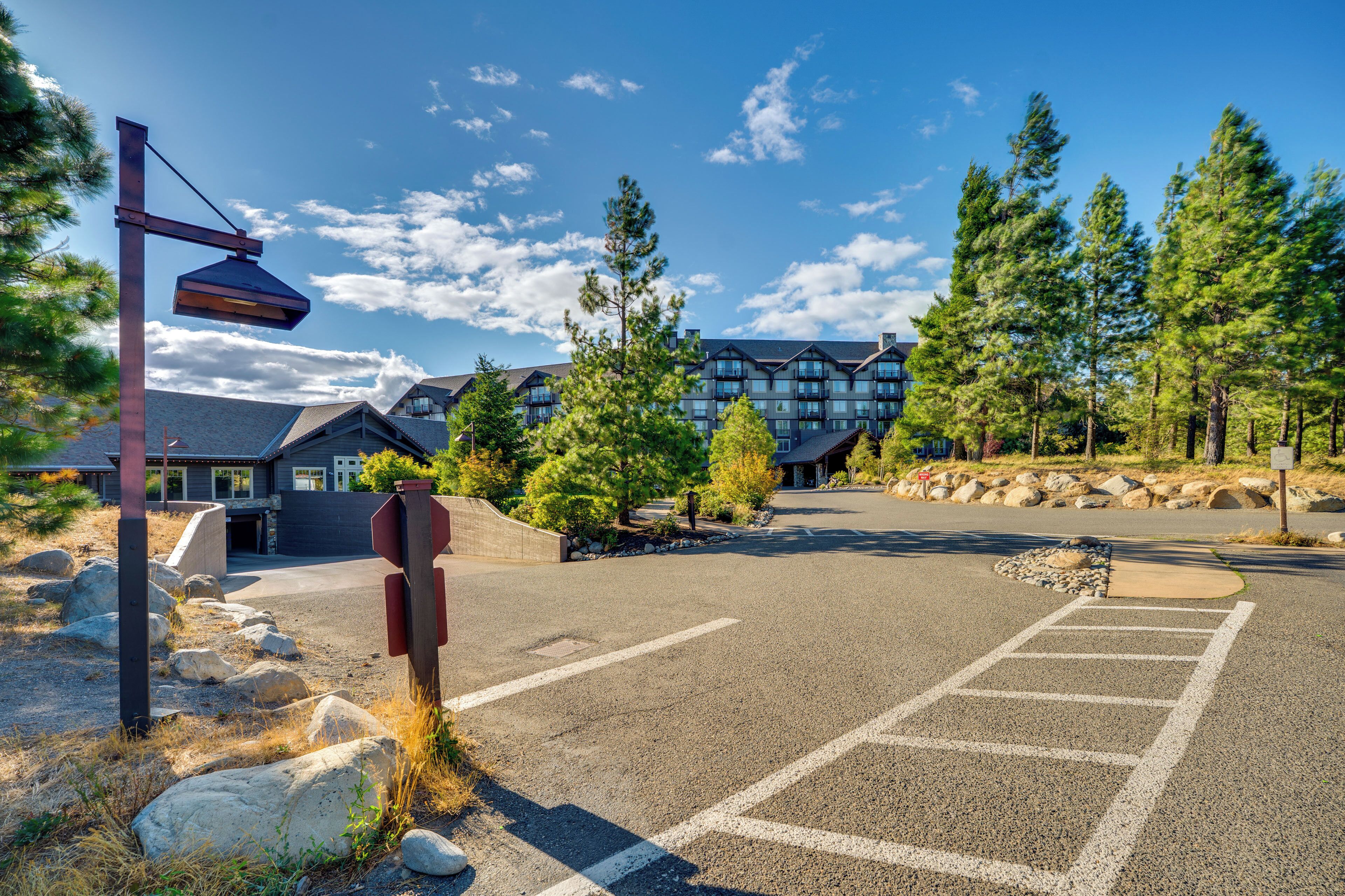 A parking lot with a building in the background, surrounded by trees and rocks.