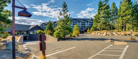 A parking lot with a building in the background, surrounded by trees and rocks.