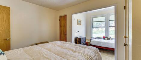 A bedroom with a large bed, a ceiling fan, and a view of the outdoors through a window.