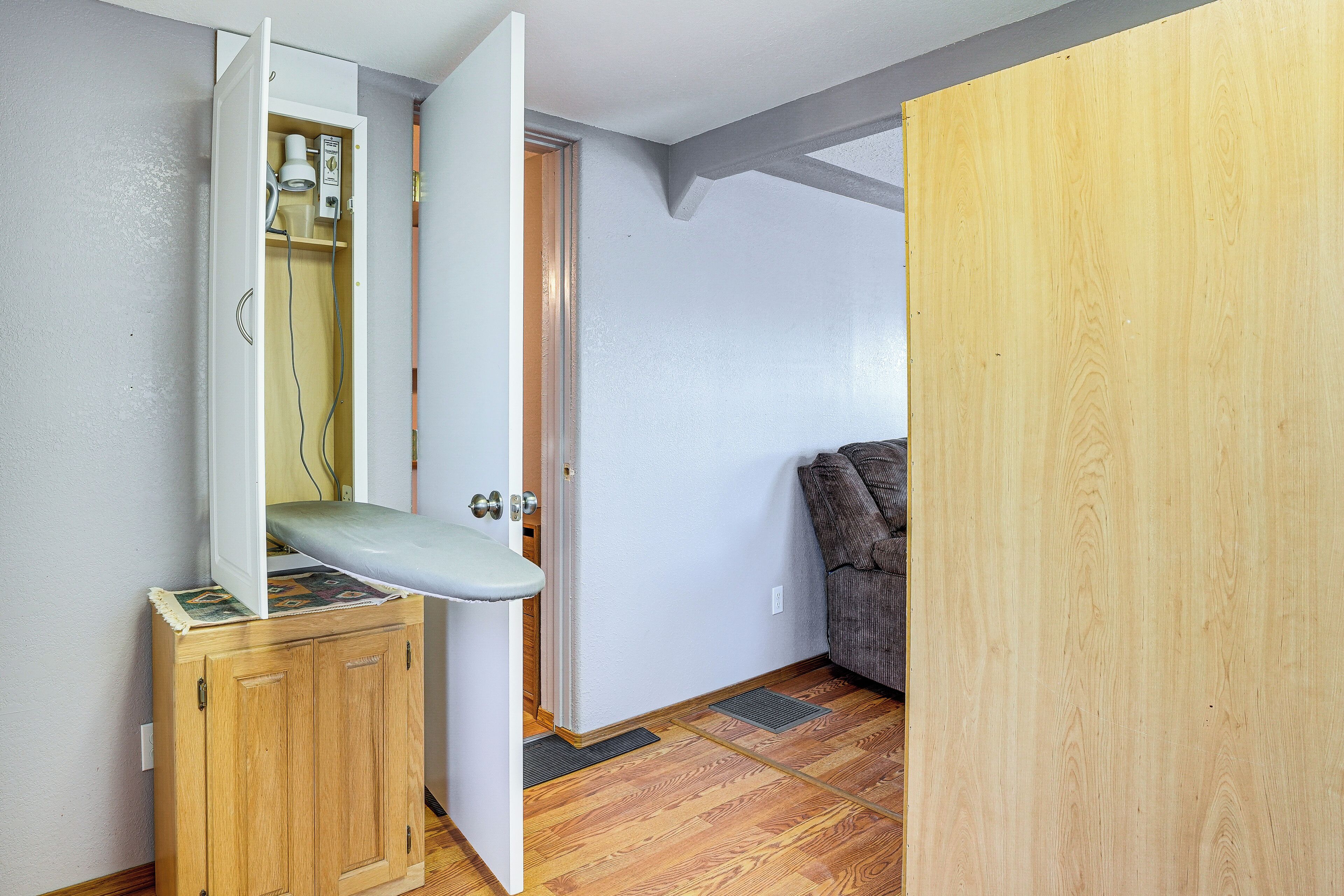 Une pièce avec un meuble en bois, une porte blanche et un canapé marron.