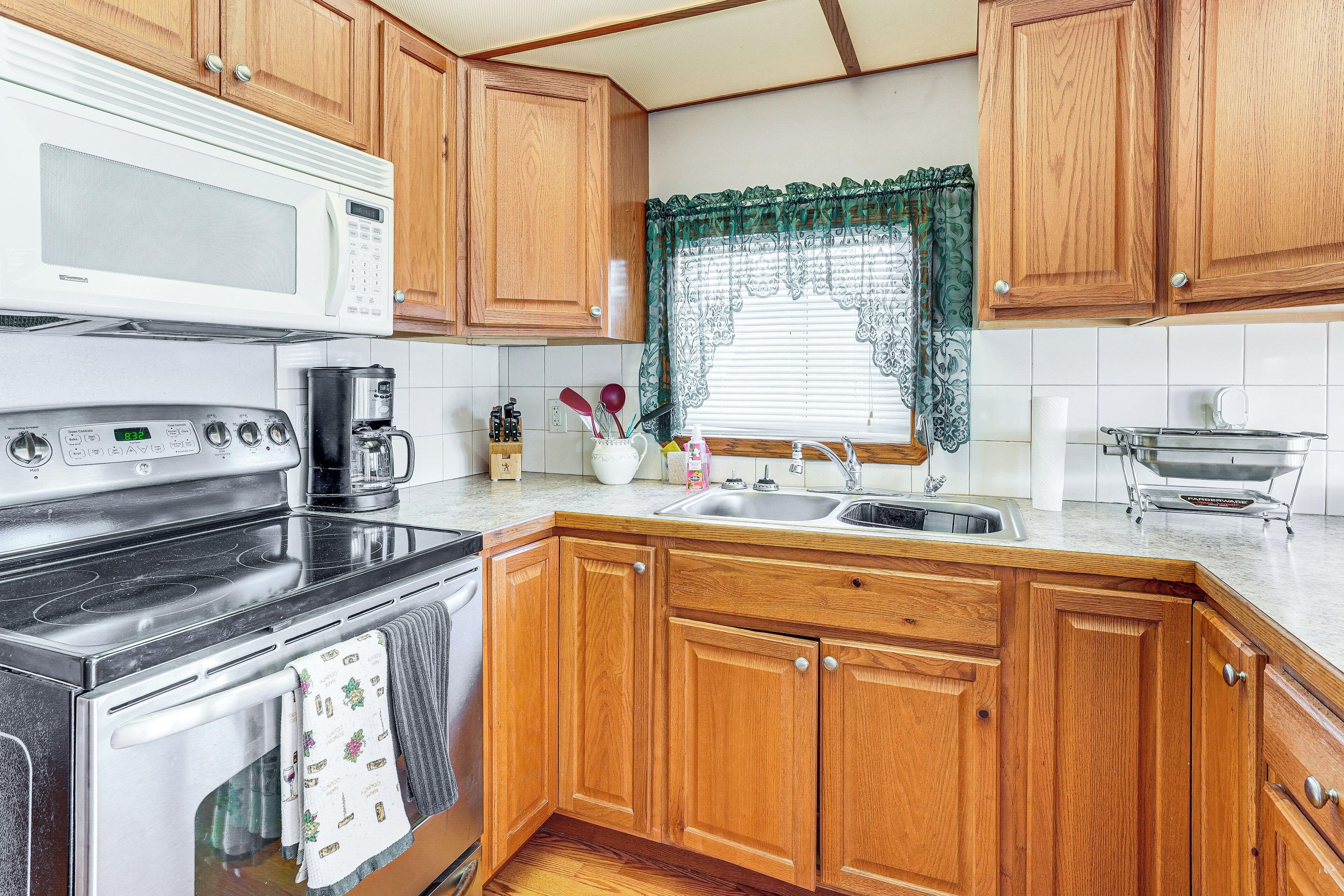 A kitchen with wooden cabinets, a microwave, a stove, a coffee maker, and a sink.