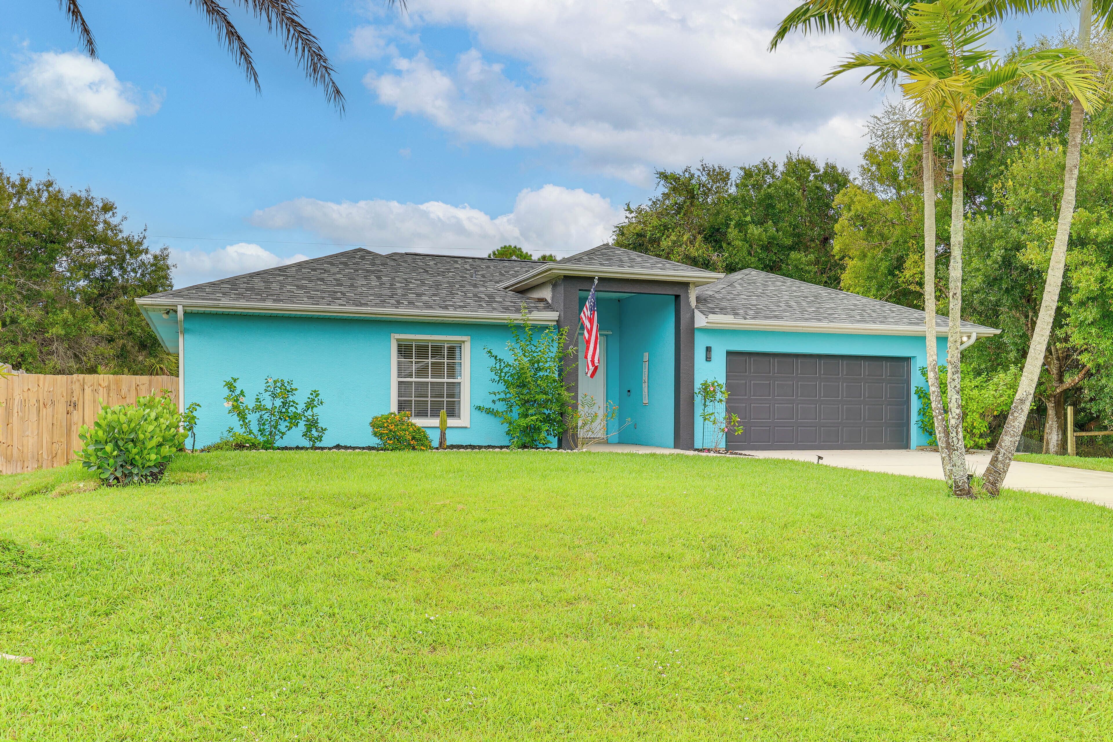 A single-story house with a blue exterior, a front garage, and a well-maintained lawn.