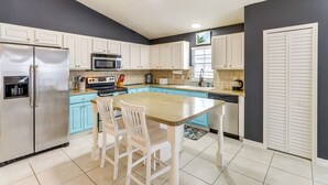 A kitchen with a central island, white cabinets, a stainless steel refrigerator, and a microwave.