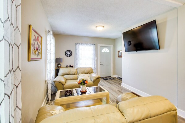 A living room with two leather sofas, a coffee table, and a flat-screen TV mounted on the wall. - 1 Mi to K-state Campus: Central Manhattan Home (Manhattan)