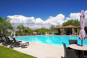 A swimming pool with lounge chairs and umbrellas, surrounded by trees and a clear sky. - Amazing Desert Views! Tucson Casita on Golf Course (Tucson)