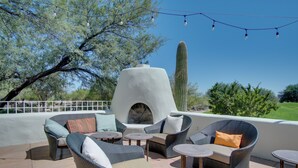An outdoor patio with wicker furniture, a stone oven, and a cactus in the background. - Amazing Desert Views! Tucson Casita on Golf Course (Tucson)