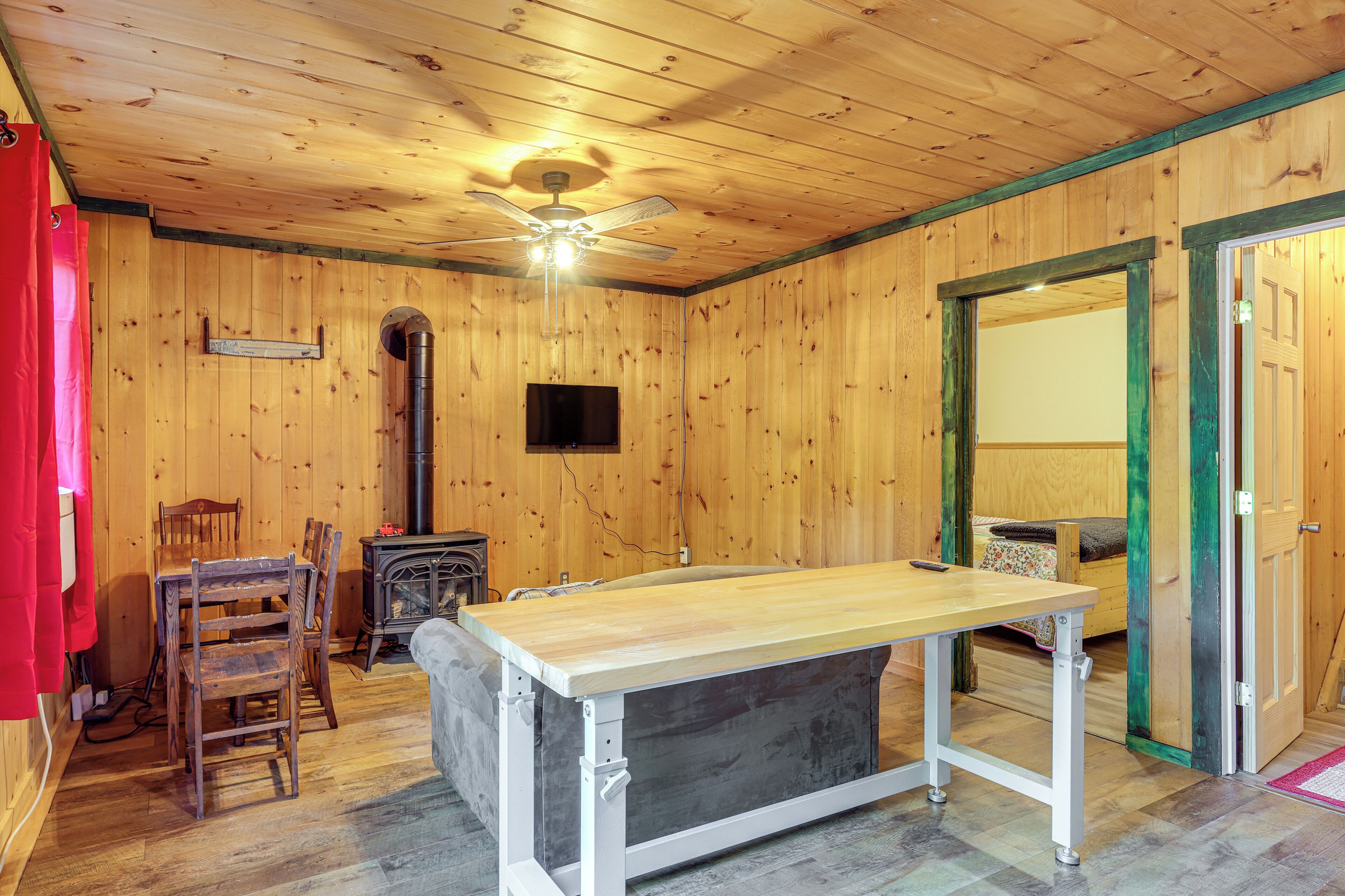 Un intérieur en bois comprenant une table à manger, des chaises, un canapé, une cheminée et un ventilateur de plafond.