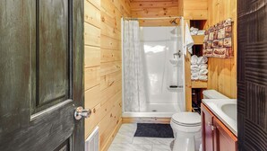 Un baño de cabaña de madera con ducha, inodoro y lavamanos.