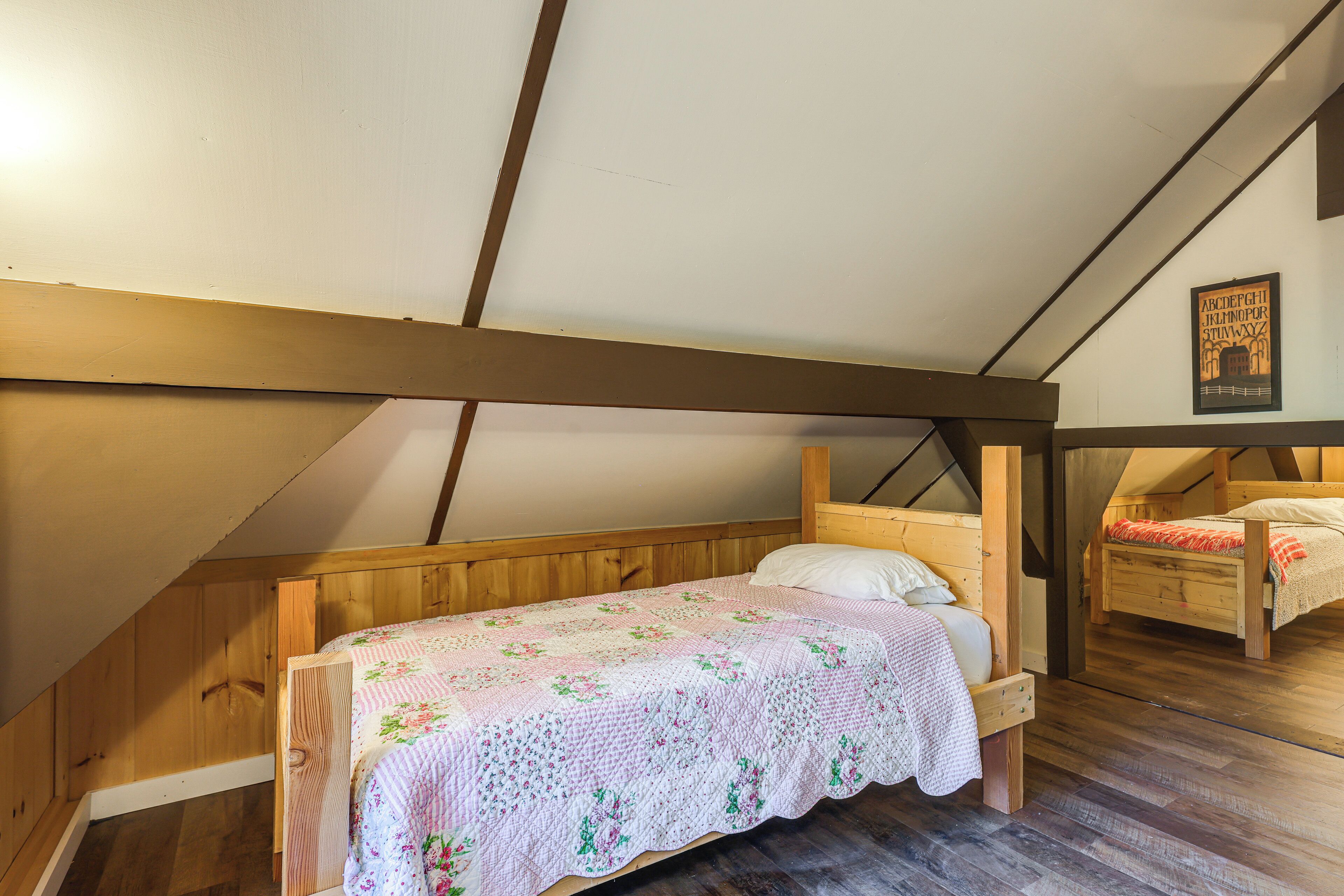 Une chambre à coucher avec un lit en bois, une courtepointe et un plafond en pente.