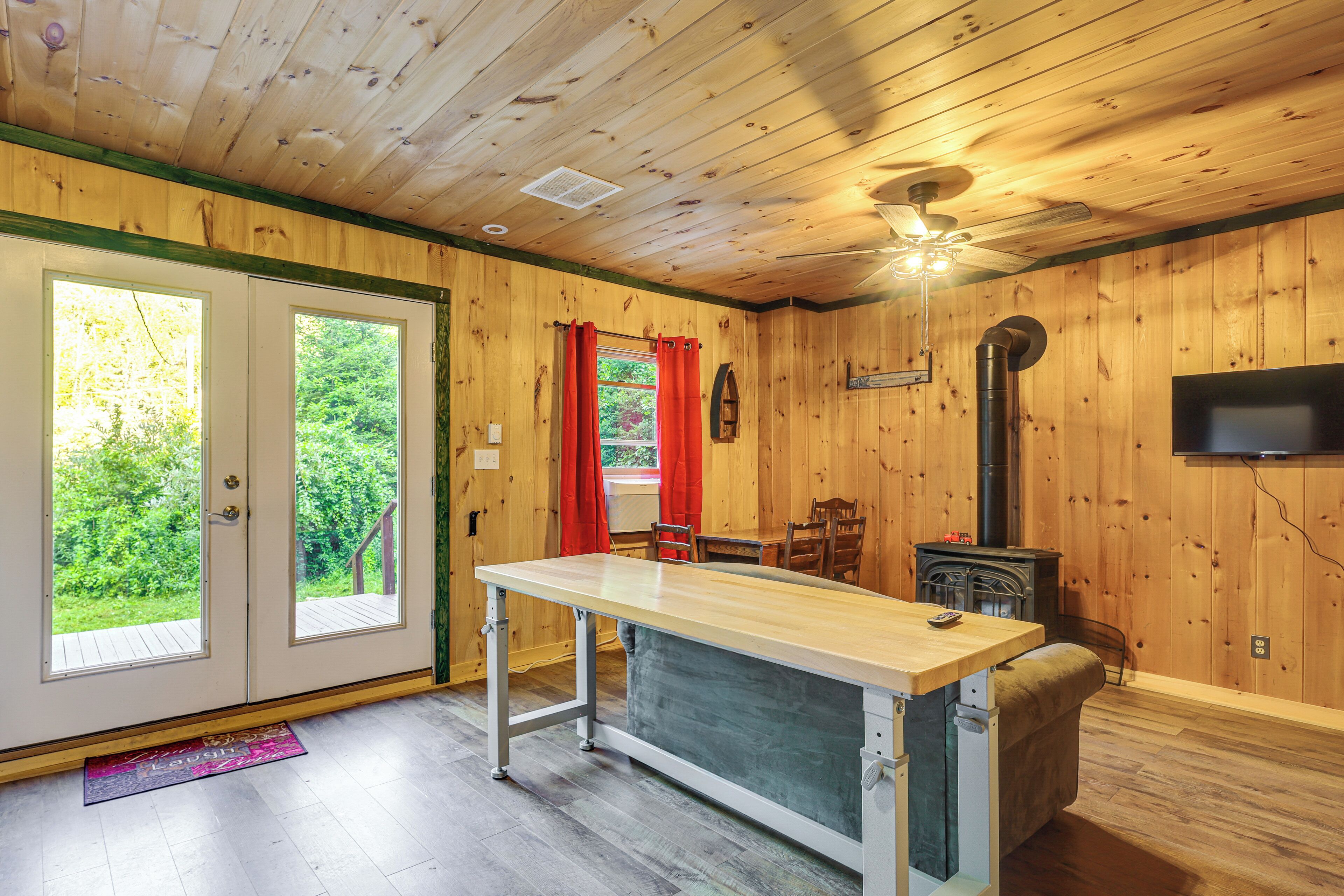 Ein Holzinnenraum mit Esstisch, Stühlen, Kamin und Fernseher.
