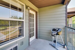 Une véranda couverte avec un chariot pour barbecue et une fenêtre donnant sur une cour.