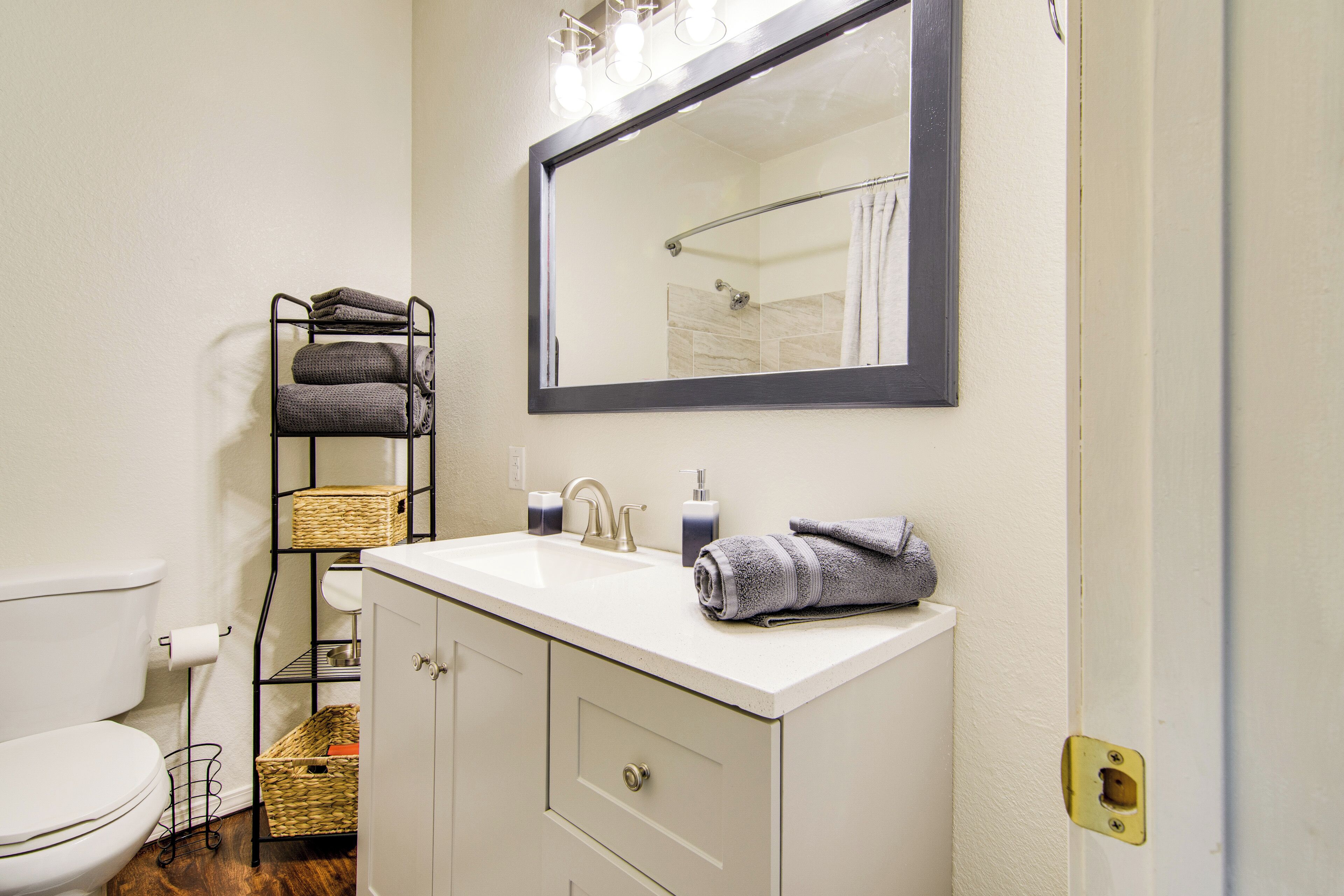 A bathroom with a white sink, a mirror, a towel rack, and a toilet.