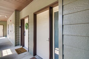 A building entrance with a wooden ceiling, a doormat, and a door with a wreath.