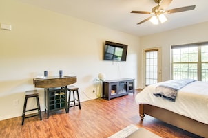 A bedroom with a bed, a desk, a chair, a television, and a window.