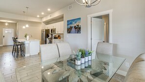 Une cuisine moderne avec des meubles blancs, un îlot central et des luminaires suspendus.