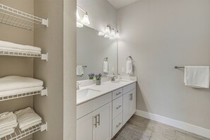 A bathroom with a double sink, white cabinets, a towel rack, and a mirror with lights. - Golf, Shop & Beach-hop: Port Charlotte Gem w/ Yard (Port Charlotte)