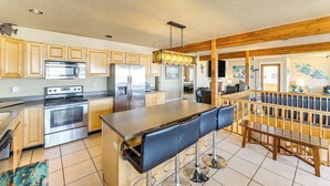 Una cocina amplia con electrodomésticos modernos, armarios de madera y una zona de bar con taburetes.