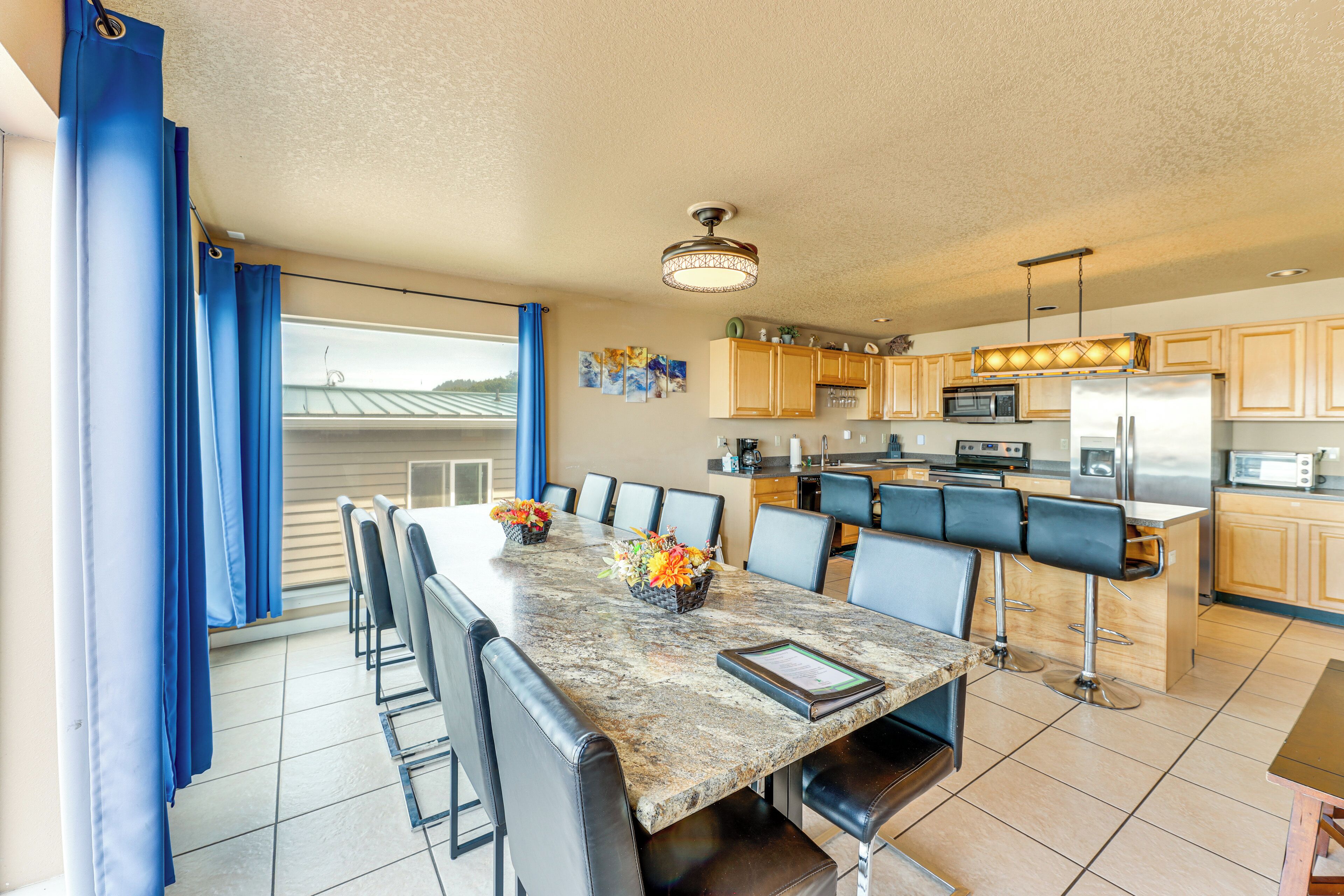 A spacious kitchen with a large island, wooden cabinets, and a dining area with chairs and a table.
