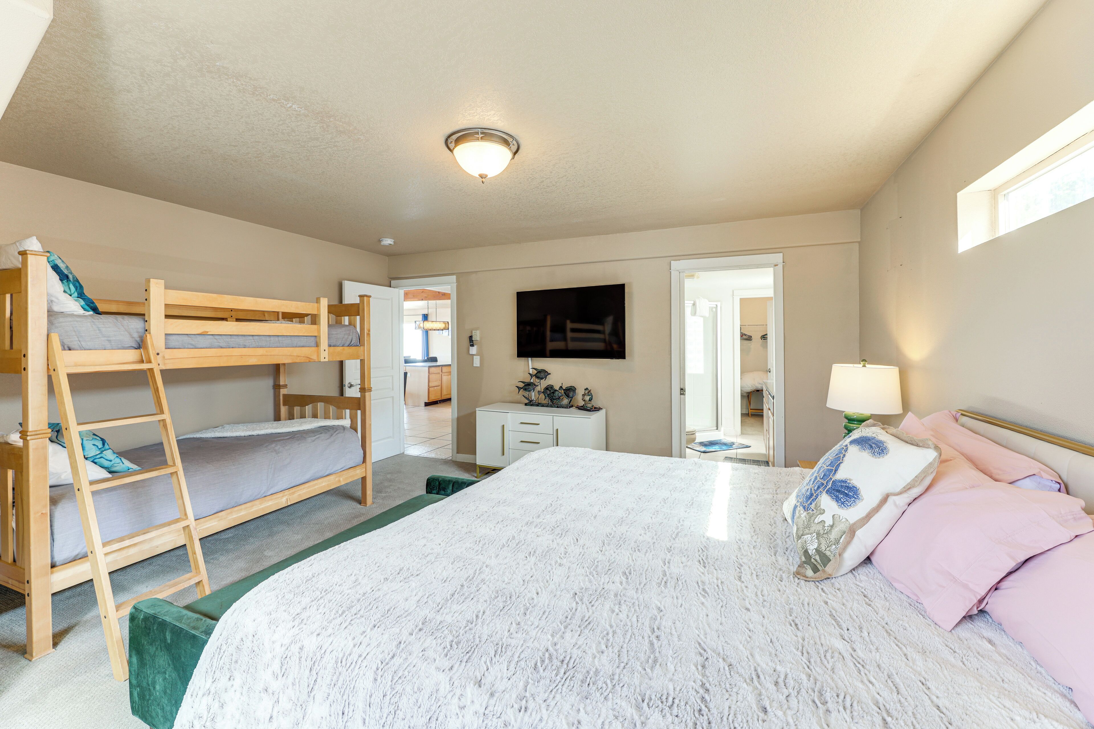 A bedroom with a bunk bed, a large bed, a desk, and a mirror.