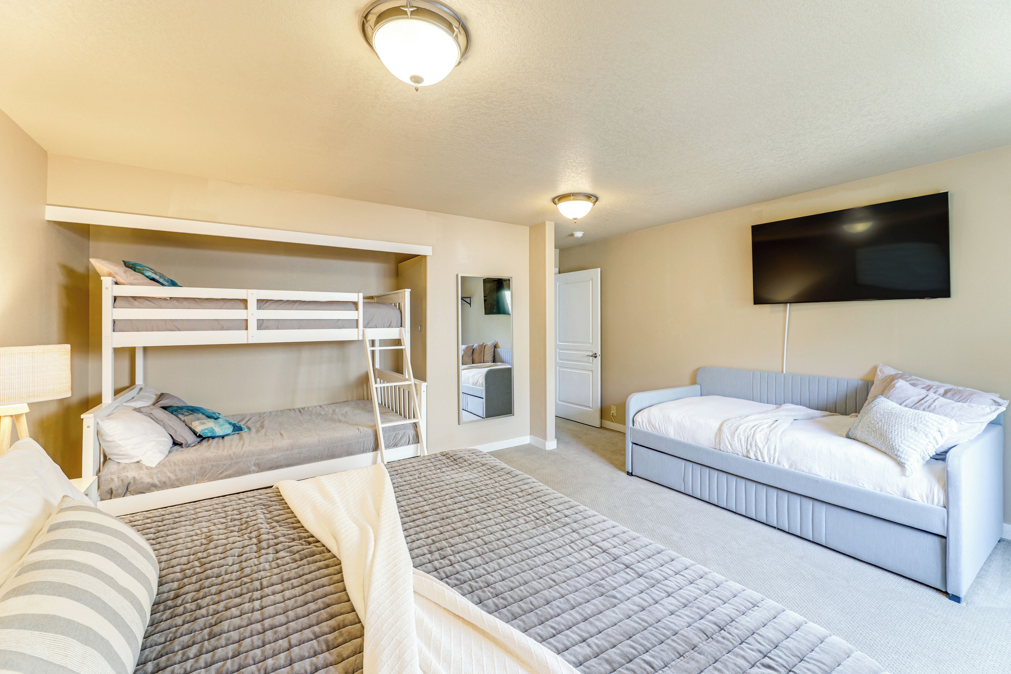 A bedroom with bunk beds, a sofa, a flat-screen TV, and a door leading to a bathroom.