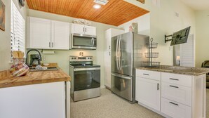 A kitchen with white cabinets, stainless steel appliances, a wooden ceiling, and a granite countertop.
