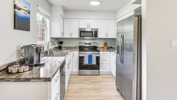 A modern kitchen with white cabinets, stainless steel appliances, and a marble countertop. - 2 Mi to State Park: Dog-friendly Niceville Home (Niceville)