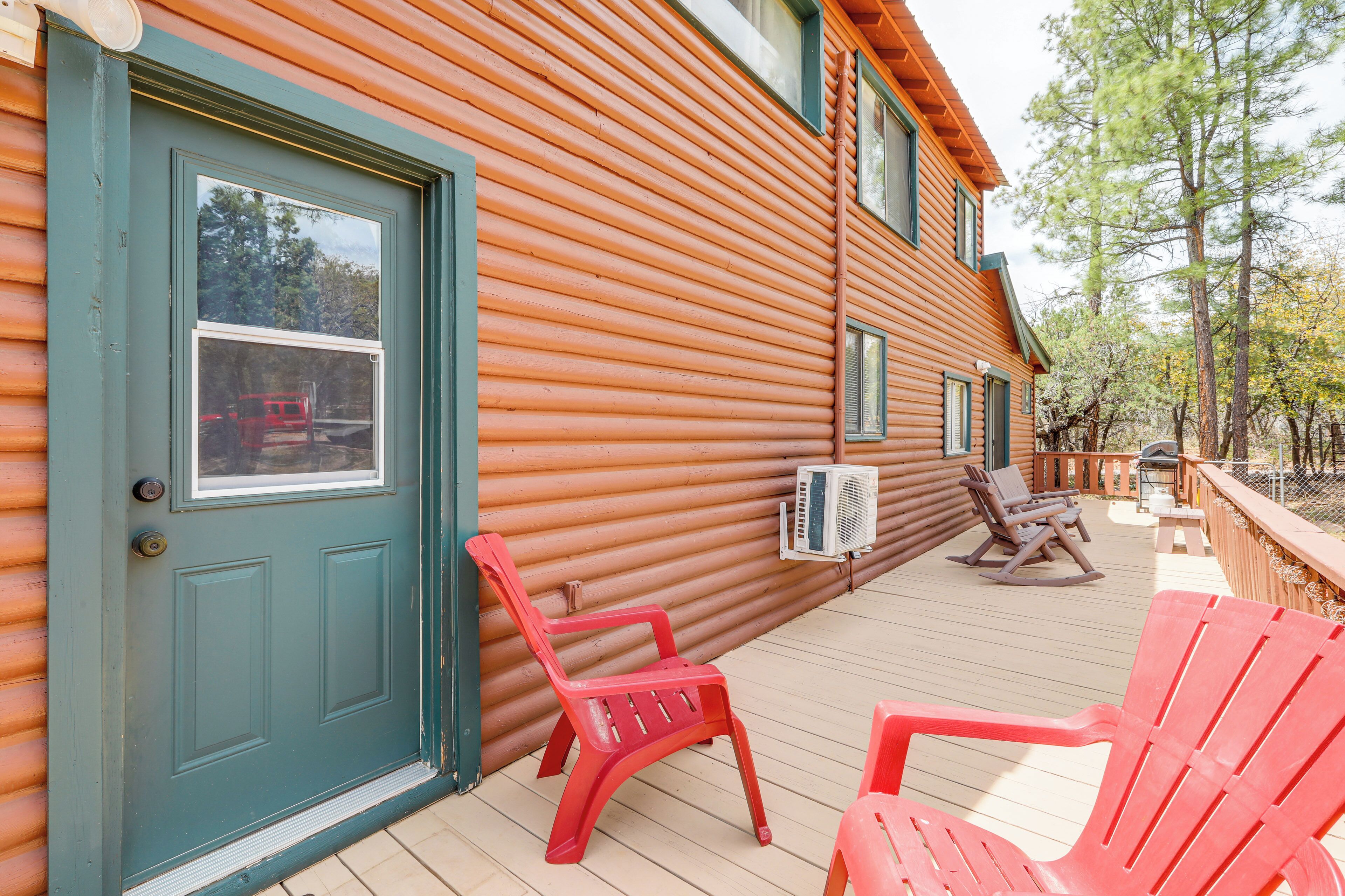 A wooden cabin with a deck, a door, and two rocking chairs.